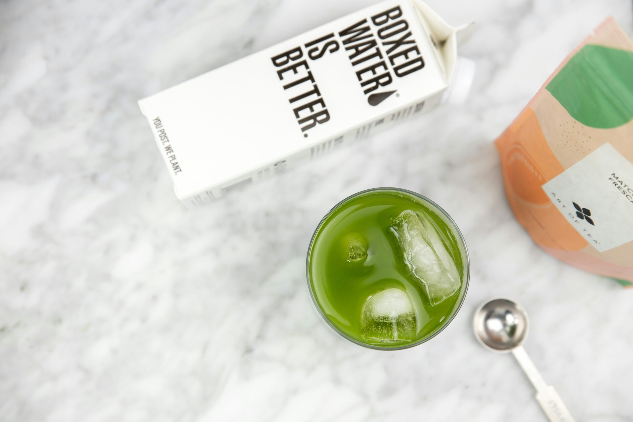 a glass of green tea next to a bottle of green tea